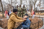 Man putting military pins on the collar of a man in wheelchair.