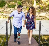 Man with prosthetic leg walking hand in hand with woman. 