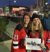 Two women in hockey jerseys holding a First Tix sign.