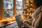 Woman shopping online in living room with Christmas tree and decorations in the background.