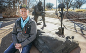 A Vietnam Veteran sitting next to a military memorial.