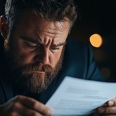 Man looking distressed reading bills.