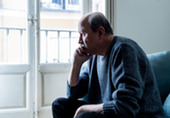 Lonely man looking outside his window.