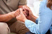 Woman and man grasping hands in compassionate gesture.