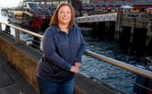 Woman smiling and leaning on a railing along a boat pier.