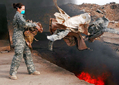 Female Service member discarding materials in a burn pit