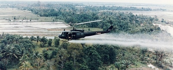 Helicopter distributing Agent Orange herbicide over forest in Vietnam