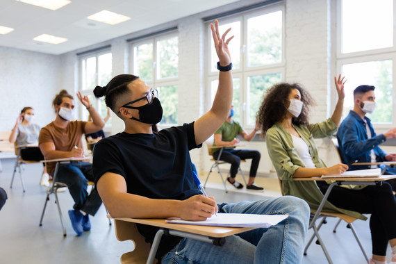 Students wearing masks in a classroom engaging in lecture