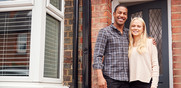 Young couple smiling in front of their brick home