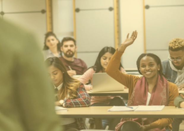 Student smiling with her hand raised in a classroom setting