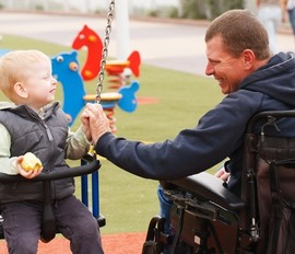 Disabled man playing with his child at the park