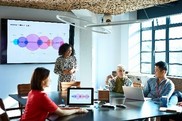 Three work colleagues sit at a conference room table while one stands
