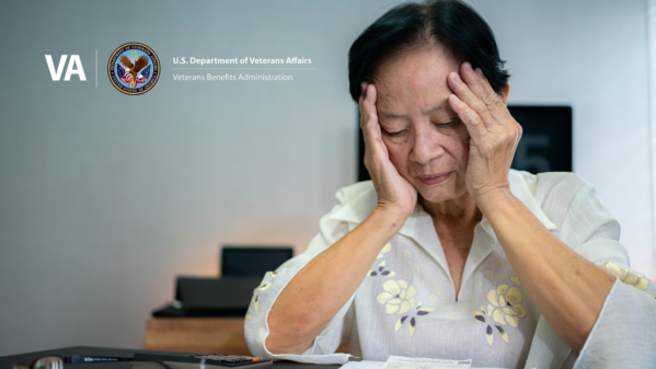 Image: elderly Asian woman holds her face in her hands, looking distraught at papers on table. VBA Logo is overlaid at top left
