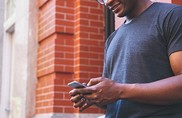 Man standing outside of a building looking down at a cell phone