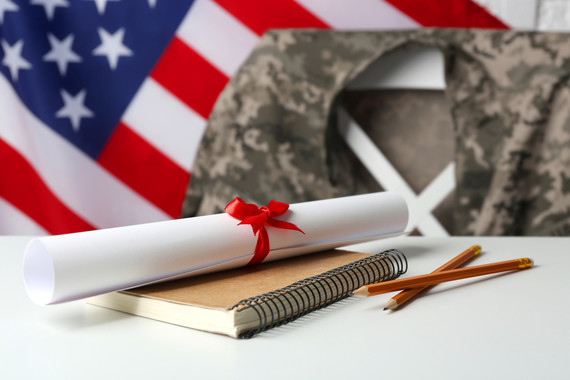 American flag, uniform shirt, desk with book, pencils and a diploma