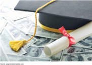 Graduation cap and diploma sit on top of one hundred dollar bills
