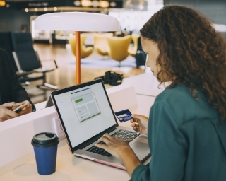 Woman with her back to the camera, sits while looking at a laptop screen.