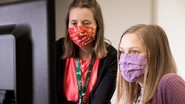 two women with masks on at a computer