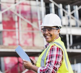 Woman wearing a hard hat and holding a tablet while participating in on-the-job training