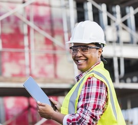 Woman wearing a hard hat and holding a tablet while participating in on-the-job training