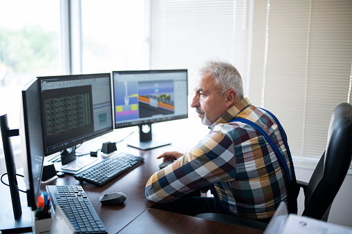 Man sits at a desk in front of three monitors