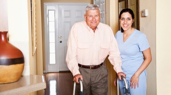 Senior man with walker being helped by his in-home care provider
