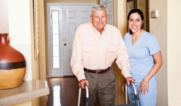 Senior man with walker being helped by his in-home care provider