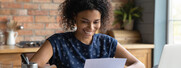 Woman smiles as she looks at a piece of paper while sitting