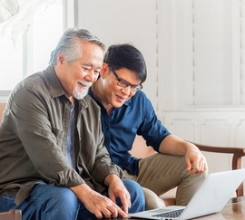 Man showing his father the Veterans Pension program on his laptop