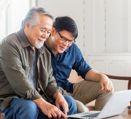 Senior man showing his son a VA OIF fraud alert on his laptop