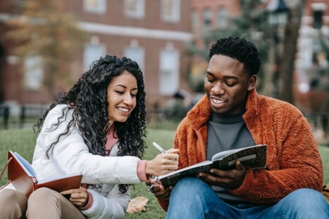 Two Students Writing In Notebook