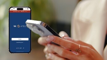 Someone holding a cell phone with a graphical image of another cell phone in the background