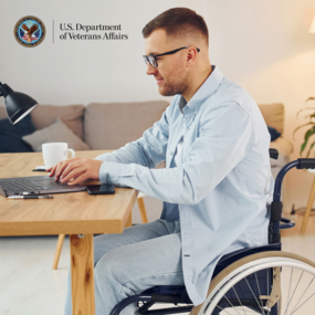 Man in wheelchair sits at desk and works on a computer 