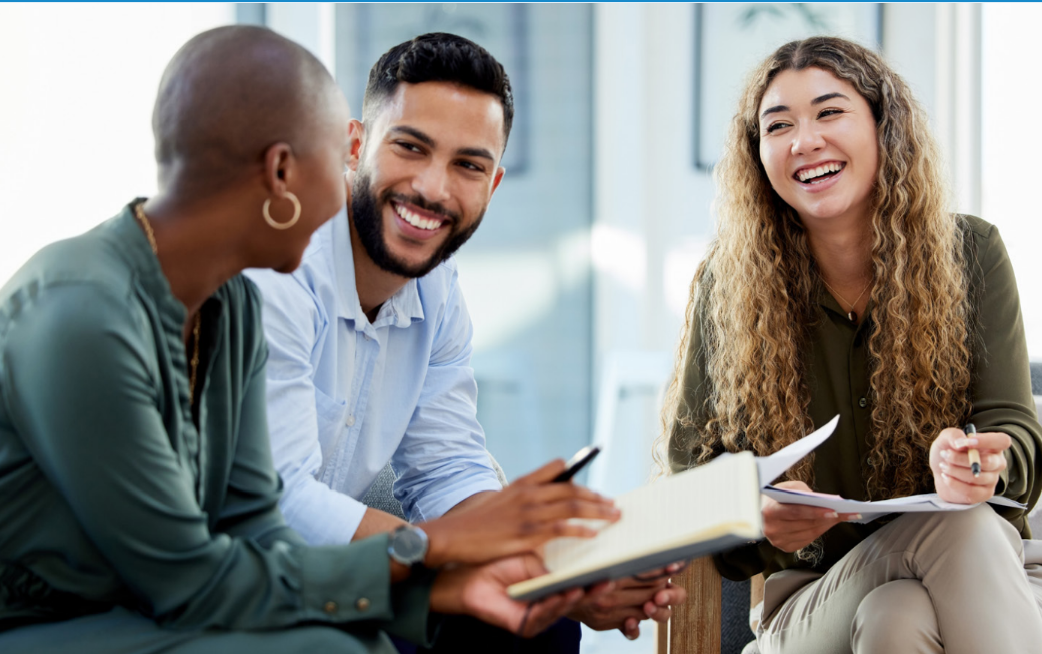 Three people sitting and smiling at one another