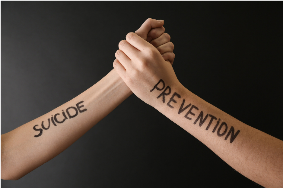 Two arms holding hands, with the words "Suicide Prevention" written on the arms, one word each arm.