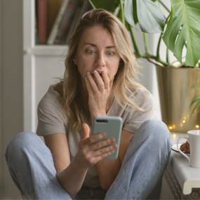 Woman gasps while looking at her smartphone