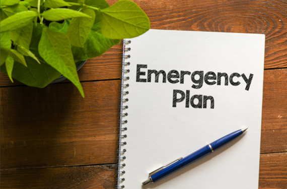 Notebook with the text “Emergency Plan” written on it with a pen on top of it.