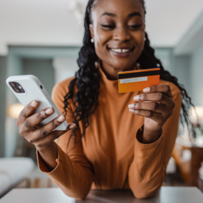 Woman with credit card in one hand and phone in the other