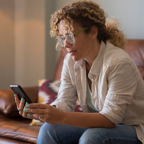 Woman sits alone on safe while looking at her phone