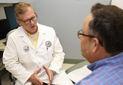 A photograph of Dr. Norman Hooten speaking with another person in an office at a VA medical center