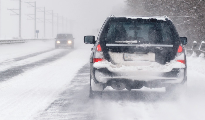 Two cars driving during a winter storm.