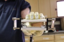 Man using a sensory enable prosthetic hand to gently squeeze two bars together