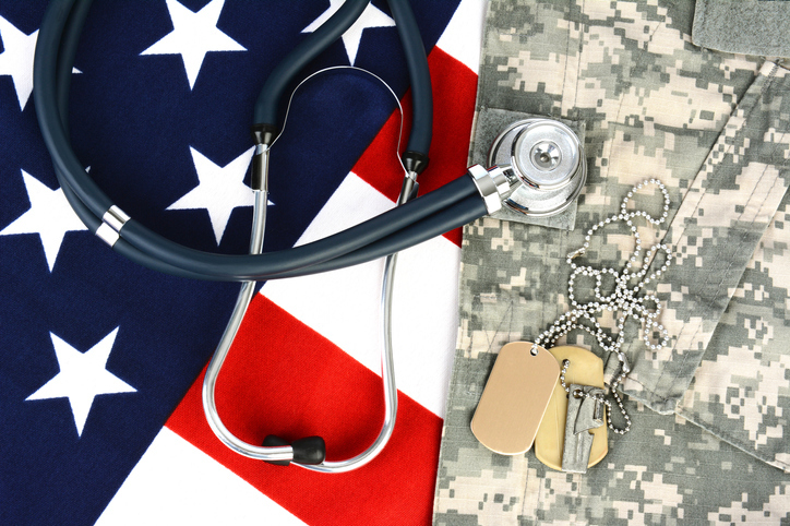 Stethoscope and dog tags laying on top of American flag and camouflage uniform