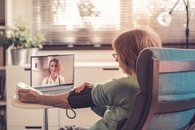 A Veteran talking to her doctor via VA Video Connect while checking her blood pressure 