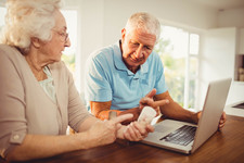 Couple using a laptop and holding pills at home