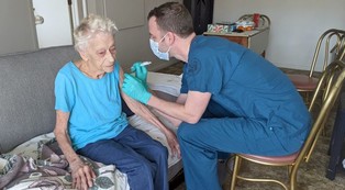 elderly woman getting vaccinated by a male pharmacist