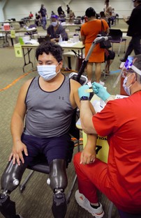 A man is sitting in a chair talking to a nurse about getting his COVID vaccination