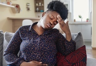 A woman sits with her hand on her lower stomach