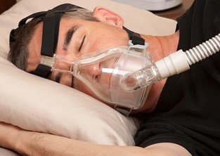 A man sleeps while wearing a CPAP machine