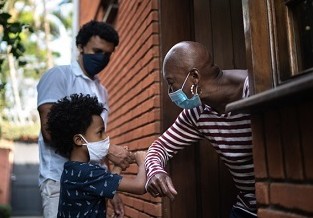 A Veteran and family greeting each other while wearing masks